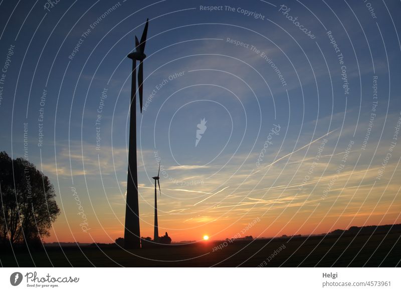 Sonnenaufgang - zwei Windräder stehen auf einem Feld vor aufgehender Sonne Windrad Windkraftanlage Morgen morgens früh Sonnenlicht Licht Schatten Landschaft