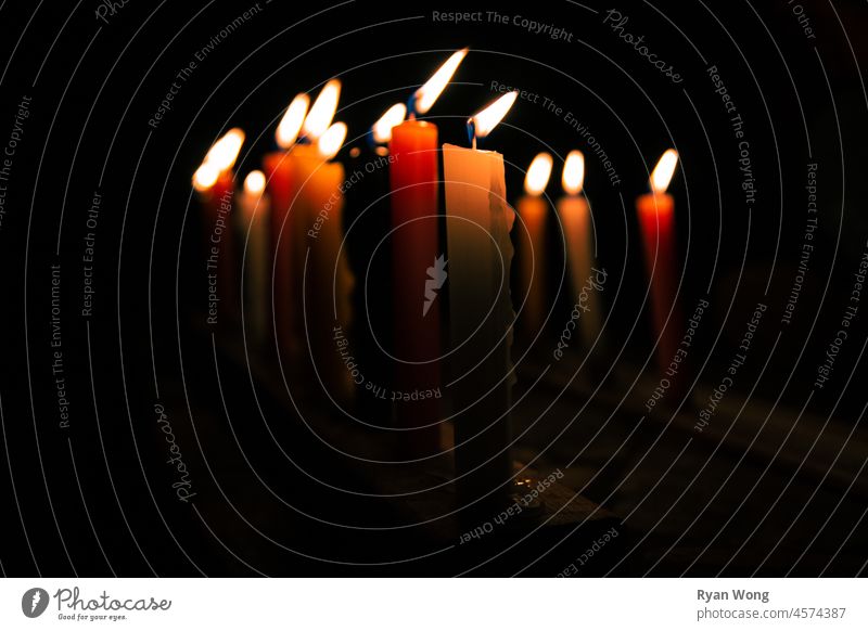 Eine Reihe bunter Kerzen in einer windigen Nacht. Gedenkstätte Erinnerungen brennend Flamme Kerzenschein schwarzer Hintergrund dunkel