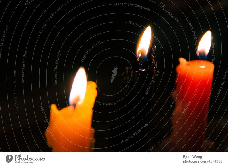 Nahaufnahme einer schwarzen Kerze auf einer Reihe bunter Kerzen in einer windigen Nacht. Gedenkstätte Erinnerungen brennend Flamme Kerzenschein
