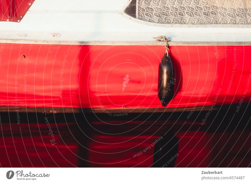 Roter Rumpf eines Boots mit Fender Wasser Spiegelung Fenster Gardine schwimmen Wassersport Sonne Reflexion & Spiegelung See Meer Sportboot Saison segeln Farbe