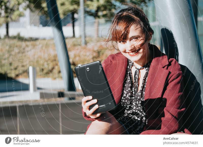 Elegante Geschäftsfrau steht außerhalb des Büros mit digitalem Tablet. Videoanruf während der Freizeit bei der Arbeit.Lächelnde hübsche Mädchen hält einen digitalen Tablet-Computer. Moderne Technologien, Kopie Raum.
