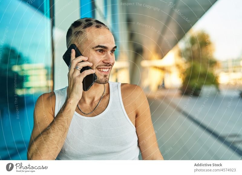 Lächelnder, exzentrischer Mann, der mit seinem Smartphone spricht benutzend Telefonanruf positiv sprechen Talkrunde Kommunizieren Stil männlich Gespräch