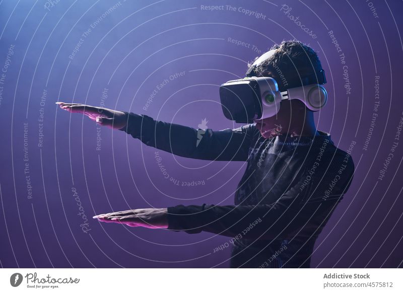 Erstaunte schwarze Frau in VR-Headset in dunklem Neonlicht futuristisch erstaunt Virtuelle Realität eintauchen neonfarbig wow Schutzbrille modern Cyberspace