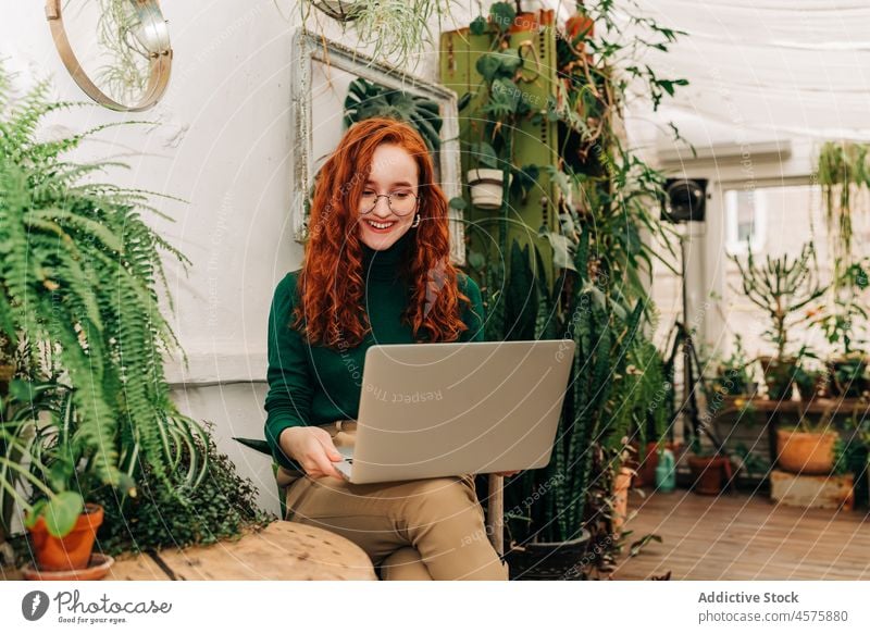 Seriöse Frau arbeitet am Laptop im Innengarten freiberuflich benutzend Arbeit online Internet Konzentration Telearbeit Garten abgelegen Browsen Job Surfen