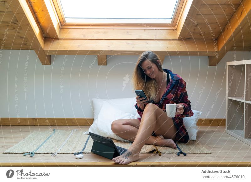 Bloggerin, die ein Mobiltelefon benutzt, während sie auf dem Boden sitzt Frau Smartphone Tablette Apparatur benutzend Gerät Beine gekreuzt soziale Netzwerke