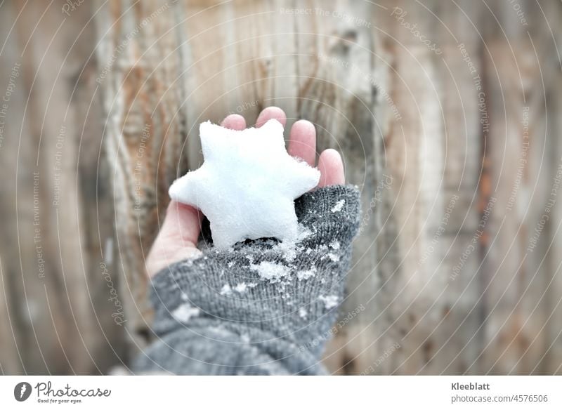 Ich schenk dir einen Stern zu Weihnachten - Frauenhand mit grauem Fingerhandschuh hält einen Stern aus Schnee und Eis Eis und Schnee Handschuh Fingerhandschuhe