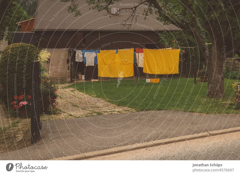 Wäscheleine mit gelber Wäsche in Vorgarten Garten Haus Fußweg Bürgersteig Einfahrt Straße Strassenansicht vintage analog trocknen wäsche trocknen Wäsche waschen