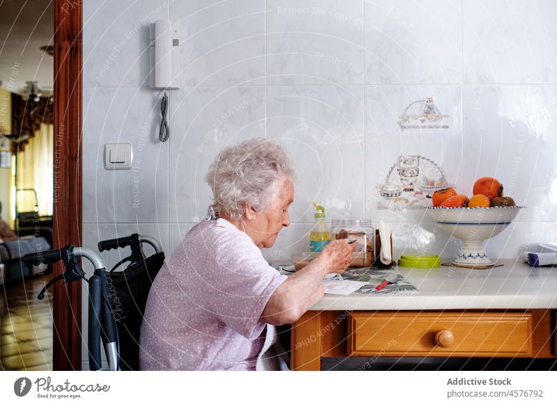 Ältere Frau im Rollstuhl beim Essen in der Küche essen Mahlzeit deaktivieren Handicap Rentnerin Lebensmittel Krankheit gealtert heimwärts zu Hause älter