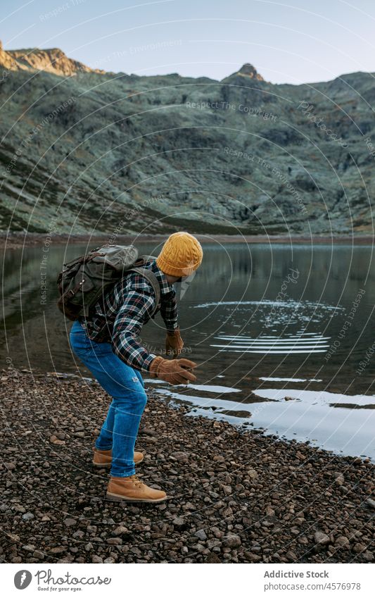 Unerkennbarer Reisender, der Steine auf der Wasseroberfläche gleiten lässt Mann Wanderer Berge u. Gebirge See Ufer Wasserseite abschöpfen werfen Natur Kamm rau
