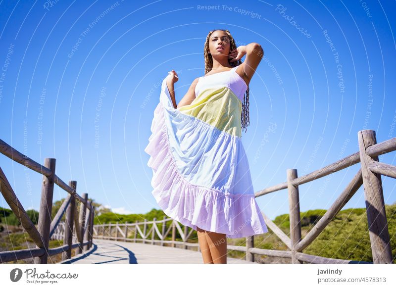 Afrikanerin in schönem Kleid auf einer Strandpromenade. Frau Mädchen Model zizi afrobraid Zopf modisch im Freien jung Person Straße Sommer gemischt Schönheit
