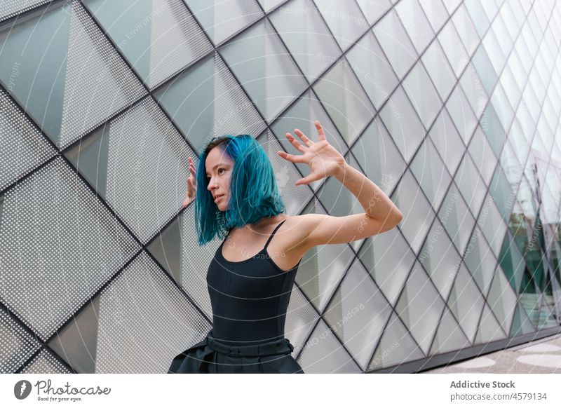 Selbstbewusste Frau tanzt an der Wand eines modernen Gebäudes Tanzen Hobby ausführen Choreographie Porträt charmant Arme hochgezogen Tänzer Vorschein trendy