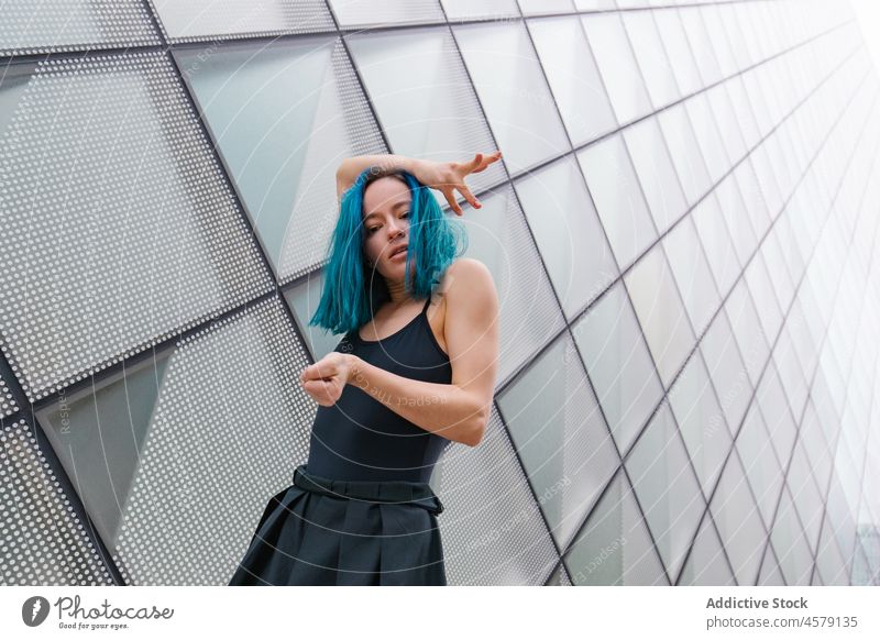 Selbstbewusste Frau tanzt an der Wand eines modernen Gebäudes Tanzen Hobby ausführen Choreographie Porträt charmant Arme hochgezogen Tänzer Vorschein trendy