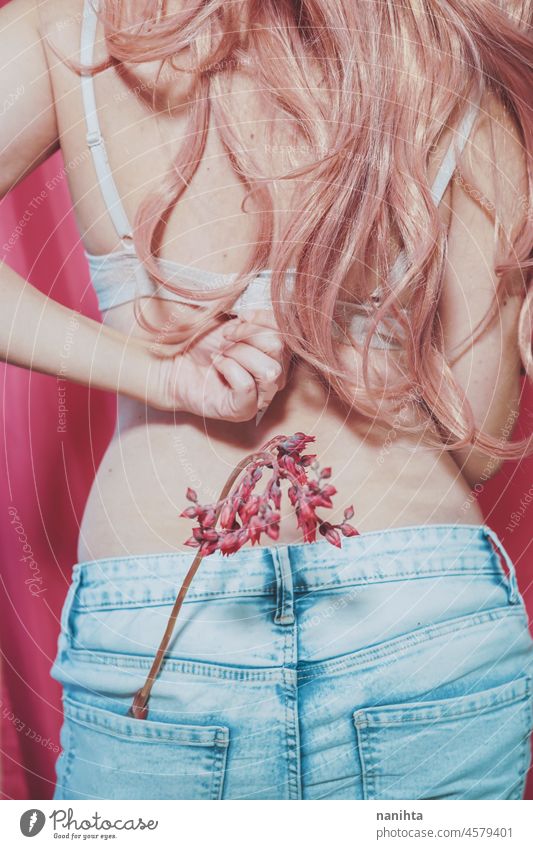 Körperbild einer echten jungen Frau, die Jeans trägt und eine exotische Blume hält positiv wirklich rosa Weiblichkeit Behaarung BH Jeanshose Unterwäsche unten