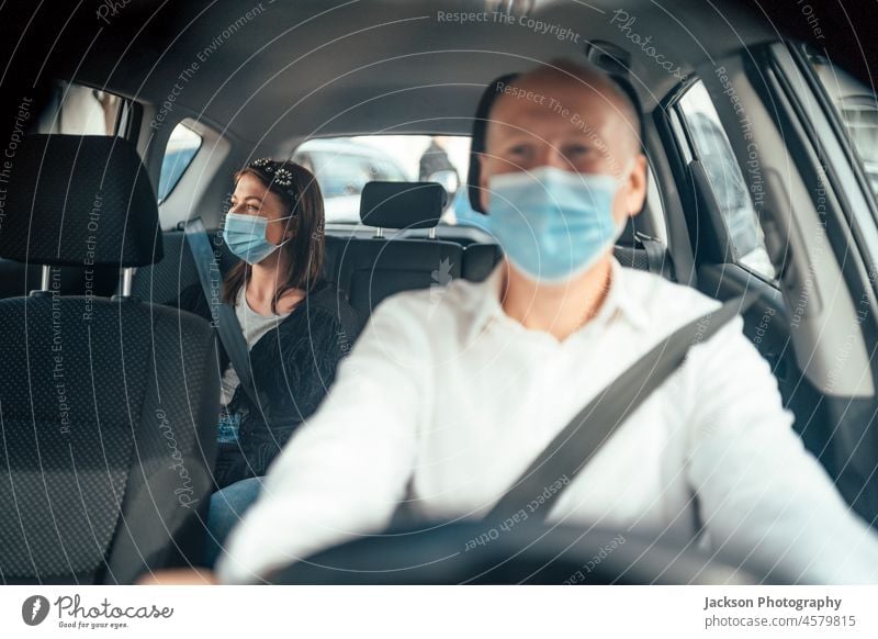 Taxifahrer in einer Maske mit einem Kunden auf dem Rücksitz mit Maske Mundschutz Fahrer uber PKW Passagier Klient Kaukasier reisen Frau Entfernung Mann Laufwerk
