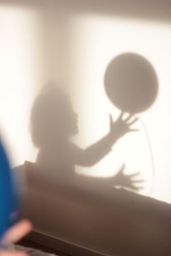 Schattenspiel Kind spielt mit Ball shilouette spielend Spielen spielendes Kind Schattenseite Schattenkind Schattendasein grau Hände fangen fangend Mensch