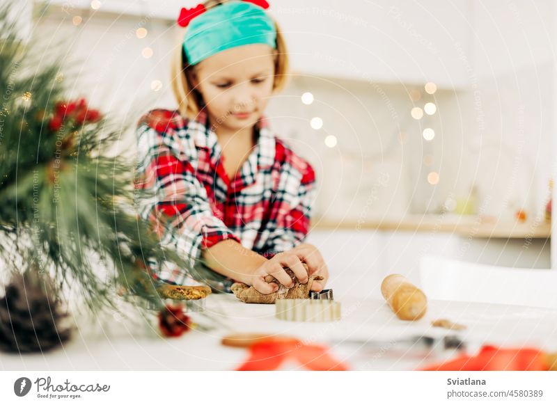 Ein bezauberndes Mädchen in einem Weihnachtskostüm backt an Heiligabend oder Silvester Weihnachtsplätzchen. Familientradition, Vorbereitung auf Weihnachten und Neujahr