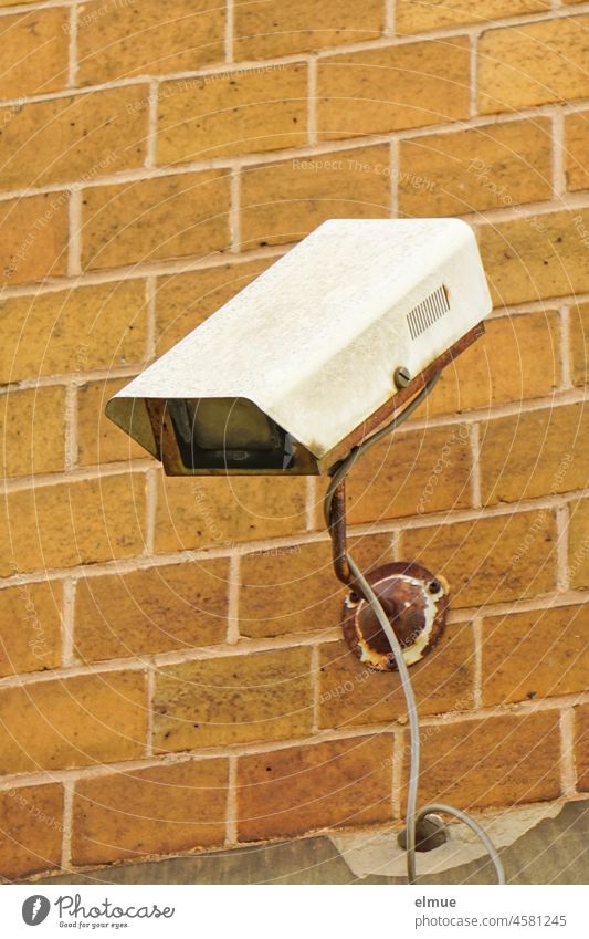 alte, defekte Überwachungskamera an einer Wand aus Ziegelfliesen / Überwachung / Marodes alte Technik Ziegelwand Kabel Fliesen Kamera Ziegelstein marode kaputt