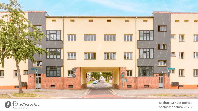 Durchfahrt eines typischen Bauhaus Wohnblockes in Pastelltönen sommer bauen Ast rot Baum geometrie siedlung Magdeburg architektur moderne minimal farbe form