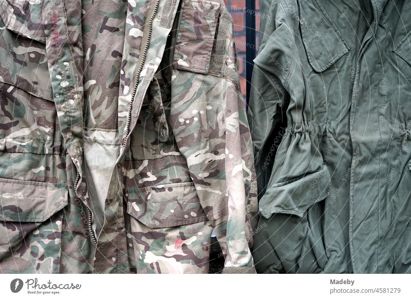 Alte Militärjacken in Oliv und Tarnfarben mit Camouflage Muster an der Backsteinmauer vor einer alten Fabrik im Stadtviertel Margaretenhütte in Gießen an der Lahn in Hessen