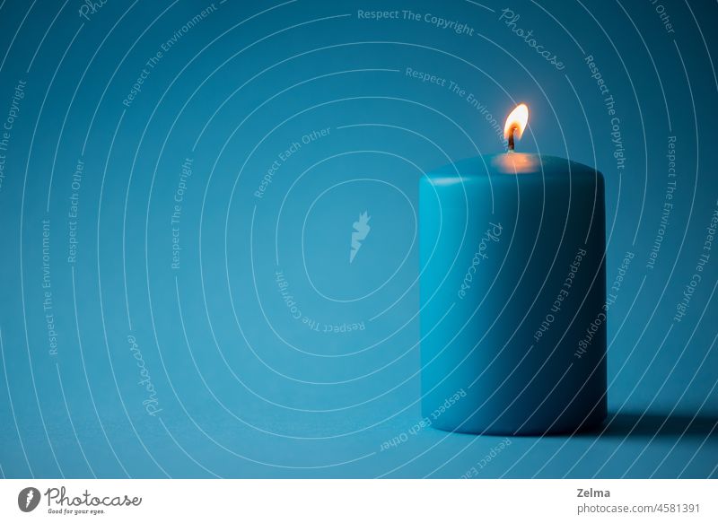 Blaue brennende Kerze isoliert auf blauem Hintergrund Kerzenschein Brandwunde Freisteller vereinzelt Blauer Hintergrund Minimalismus Feuer Flamme