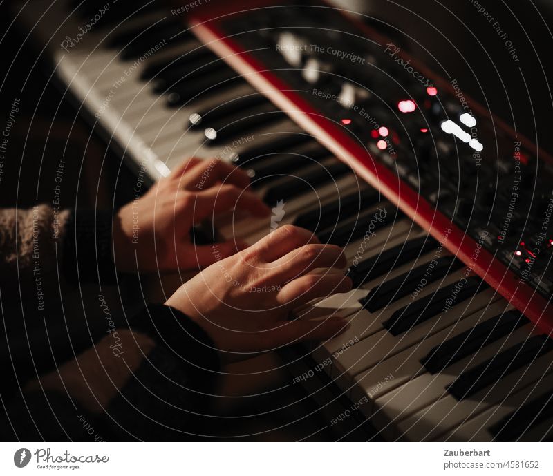Mädchen spielt nachts auf rotem Keyboard, Hände auf der Tastatur Hand songwriting Tasten Knöpfe Regler Musik spielen Musik machen Musikinstrument Nahaufnahme