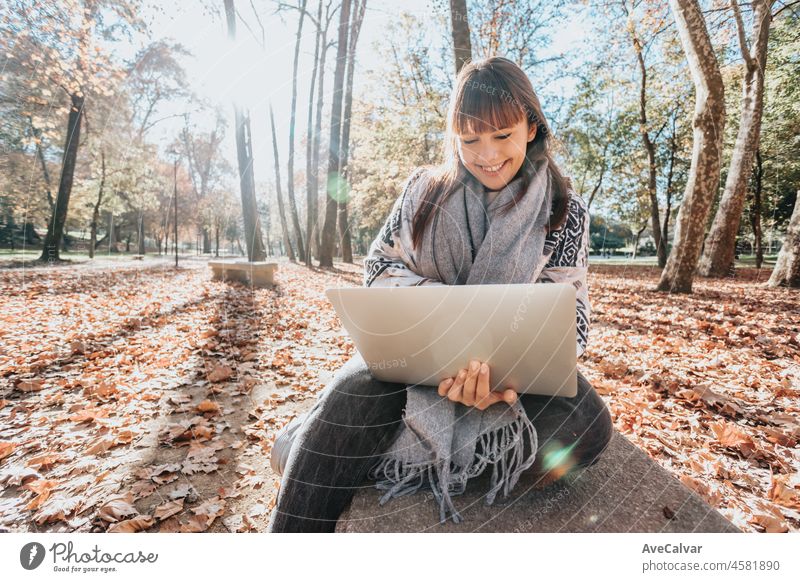 Junge Streamer kaukasischen Mädchen außerhalb mit einem Laptop zu überprüfen, Arbeit, glücklich und lächelnd Haltung. Junge und moderne trendigen Stil. Herbstliche Jahreszeit. Arbeiten überall, finanzielle Freiheit, Investitionen