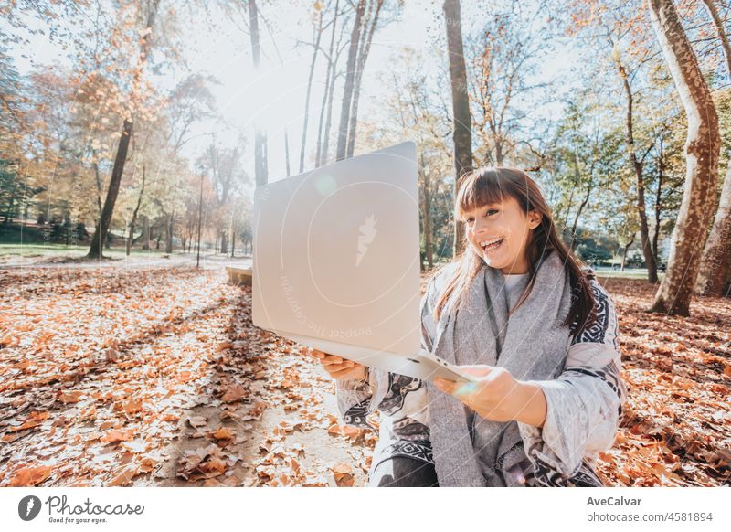 Junge Streamer kaukasischen Mädchen außerhalb mit einem Laptop zu überprüfen, Arbeit, glücklich und lächelnd Haltung. Junge und moderne trendigen Stil. Herbstliche Jahreszeit. Arbeiten überall, finanzielle Freiheit, Investitionen