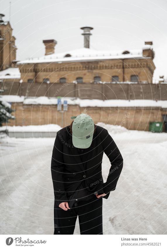 Draußen ist es kalt. Winterzeit. Eine Frau in einem schwarzen Anzug und einer grünen Mütze geht in der Stadt spazieren. Der Drehort ist Vilnius, Litauen. Schnee