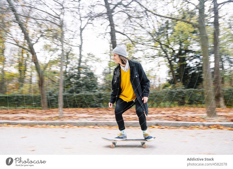 Junge Skaterin fährt Skateboard in einem herbstlichen Park Frau Mitfahrgelegenheit heiter Herbst Hobby defokussiert Glück Straße Asphalt lässig jung Natur