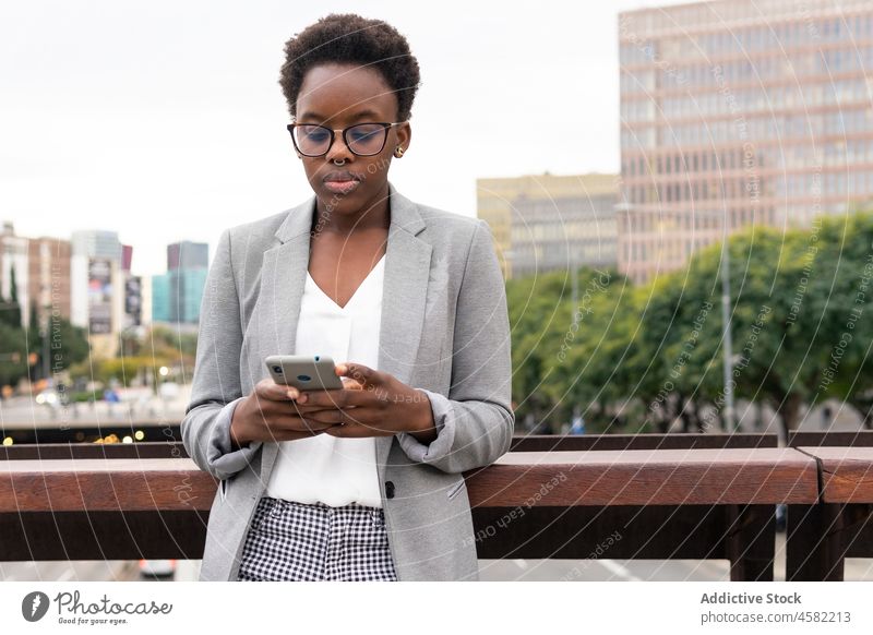 Junge afroamerikanische Frau benutzt Smartphone auf Balkon benutzend Browsen Funktelefon Geschäftsfrau Arbeiter formal Mitarbeiter Business Surfen Exekutive