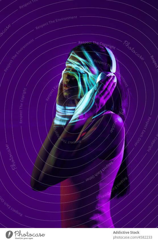 Brasilianische Frau mit Kopfhörern und Lichtschatten im Gesicht Stil trendy fluoreszierend Porträt Projektor neonfarbig cool Musik Gesang leuchten Schatten
