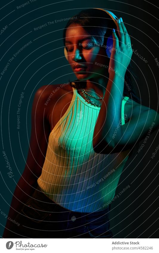 Brasilianische Frau mit Kopfhörern im Studio mit Schatten Stil trendy Atelier Tanzen fluoreszierend Musik ultraviolett Discokugel Porträt Gesang meloman