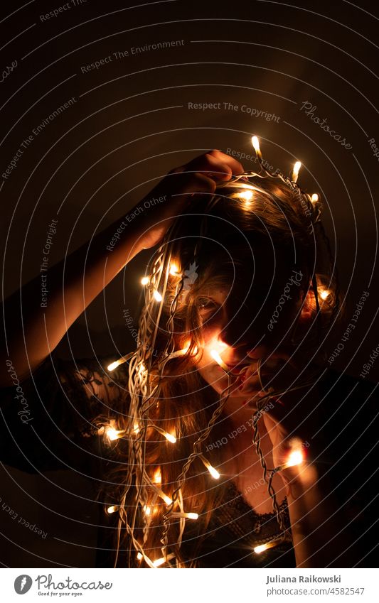 Frau mit Lichterkette Studioaufnahme Schatten Junge Frau künstlerisch Kunst melancholisch Erwachsene elegant geheimnisvoll Kitsch Weihnachtsbaum glänzend