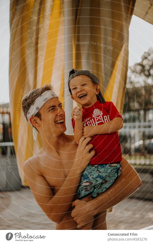 Mann kitzelt kleines Kleinkind am Pool an einem sonnigen Tag Papa Vater Onkel Familie reisen Abenteuer Vaterschaft Zusammensein Spaß Freude Glück Resort