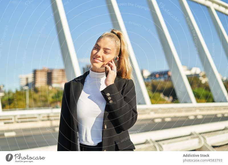 Junge Frau spricht auf einer Brücke im Sonnenlicht mit ihrem Handy Smartphone Großstadt Apparatur benutzend Funktelefon Gerät Straße sprechen reden Gespräch