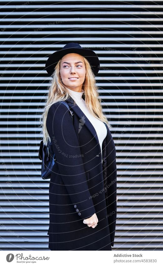 Stilvolle lächelnde junge Frau in schwarzer Jacke und Hut Mode trendy Lächeln Rucksack blond lässig Großstadt urban Glück Leder Outfit Herbst Mantel
