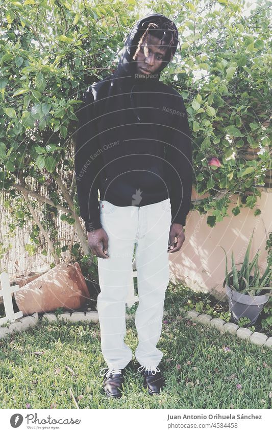 Junger schwarzer Mann posiert in einem Garten jung Schwarzer Mann Afrikanisch Pflanze Gras Mode modisch urban Stil bizarr Typ ernst Person Menschen Lifestyle