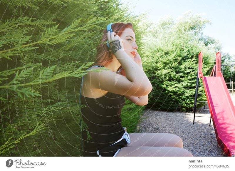Junge sportliche Frau beim Musikhören passen Lifestyle Sport Gesundheit im Freien Park Kopfhörer Technik & Technologie Sommer Sonnenlicht Licht positiv Körper