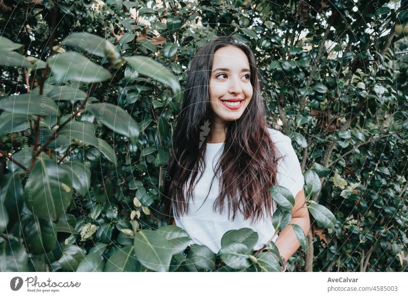 Afrikanisches arabisches junges Mädchen zwischen grünen Blättern, das lächelt und in die Kamera grüßt. Natürliche isoliert. Soziales Netzwerk Tag in der Natur Konzept. Schönheit Porträt. Platz für Text und Zusätze. Gesundheit.
