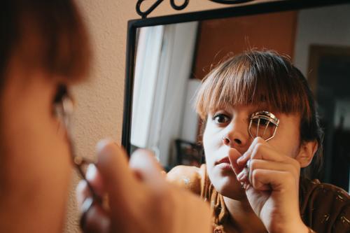 Junge Frau mit Augen Make-up Konturen Anwendung Lippenstift tun Make-up zu Hause immer bereit und Schönheit. Schaut in den Spiegel, malt ihre Augen mit schwarzem Eyeliner. Close-up.beauty und Selbstpflege Make-up