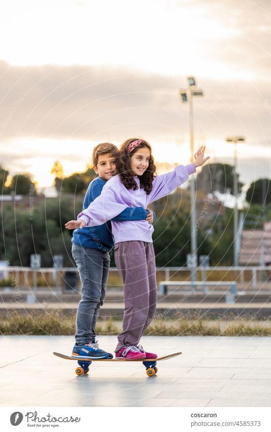 Zwei Kinder fahren zusammen mit einem Skateboard aktiv Aktivität Gleichgewicht Holzplatte Junge Kindheit genießen genießend Familie Freunde Spaß Spiel Mädchen