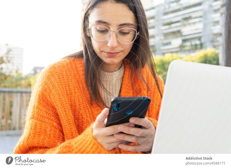 Frau surft auf dem Smartphone, während sie mit dem Laptop arbeitet freiberuflich Benachrichtigung Fokus Messenger abgelegen lesen Mobile Browsen Nachricht