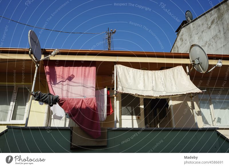 Balkon mit Tüchern als Sonnenschutz und Satellitenschüsseln im Sommer bei blauem Himmel und Sonnenschein in Adapazari in der Provinz Sakarya in der Türkei Licht