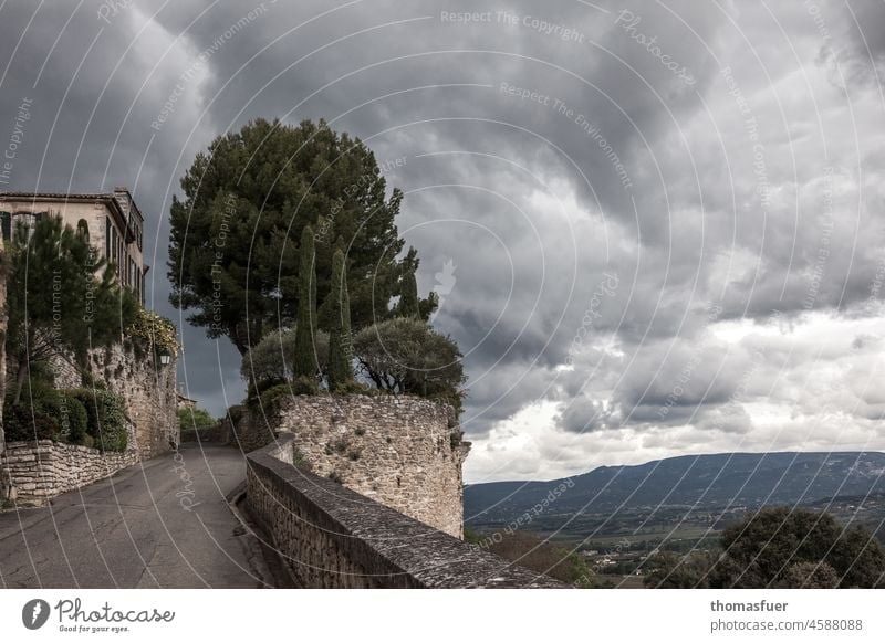 Pinie, kleine Zypressen, alte Mauer und Haus vor Wolken, Himmel in südlicher Landschaft Provence pittoresk Picturesque südliche Landschaft Frankreich Natur