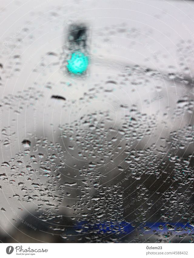 Regentropfen auf der Scheibe und eine grüne Ampel Regentag Autofahren Autofenster FRontscheibe Verkehr unterwegs Verkehrszeichen Außenaufnahme Straßenverkehr