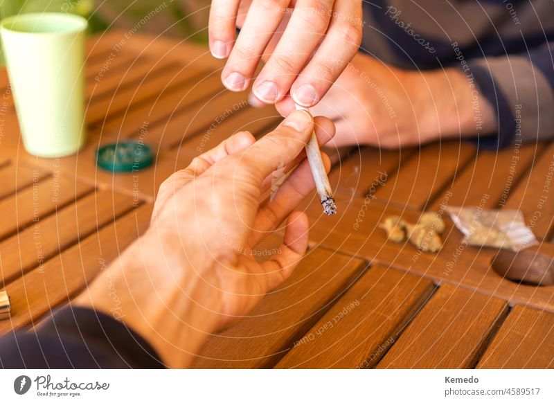 Unbekannte Person, die ihrem Freund auf einer Party einen Marihuana-Joint reicht. Cannabis Gelenk Unkraut teilen Pass Zusammensein kennenlernen Zigarette