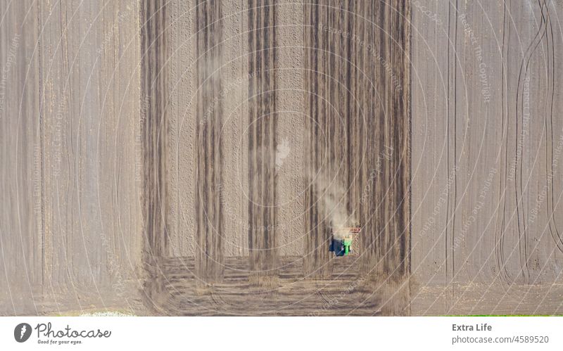 Luftaufnahme eines Traktors beim Ziehen eines Grubbers über ein landwirtschaftliches Feld, Ackerland oben quer Ackerbau Agronomie anbaufähig Land kultivieren