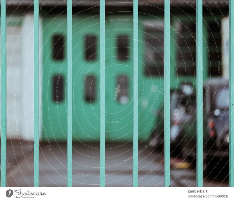 Grünes Tor hinter grünen Gitterstäben vor Hofeinfahrt Werkstatt geschlossen Stäbe vertikal städtisch geringe Tiefenschärfe Metall Eingang Gebäude verschlossen