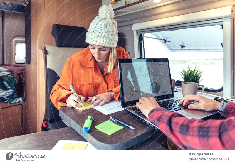 Frau und Mann bei der Telearbeit in einem Wohnmobil Laptop schreibend Haftnotizen Kleintransporter Ausflug abgelegen Arbeit Zusammensein Menschen Tabelle Job