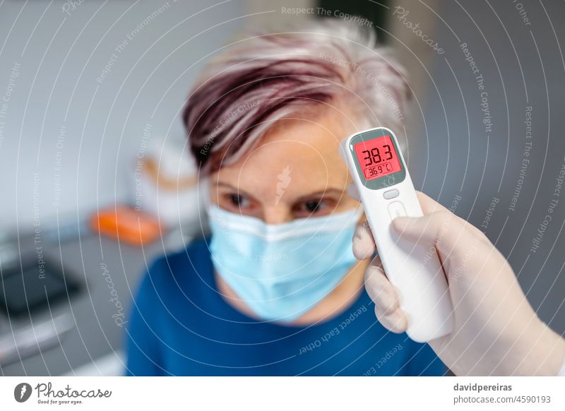 Ältere Frau mit Fieber, deren Temperatur von ihrem Arzt gemessen wird Senior Infrarot-Thermometer Coronavirus omicron Delta Symptom Schutzmaske Überprüfung reif